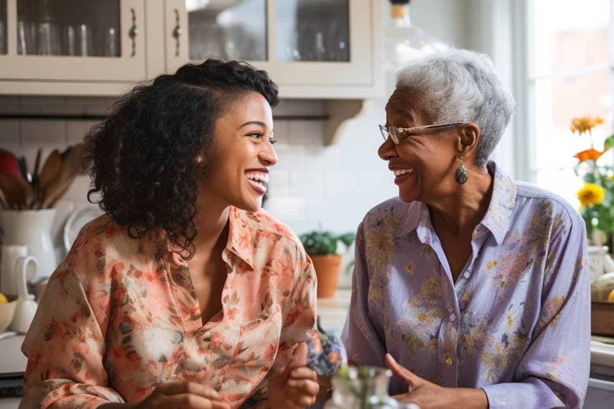 Younger and older women sharing a joyful conversation in a bright kitchen